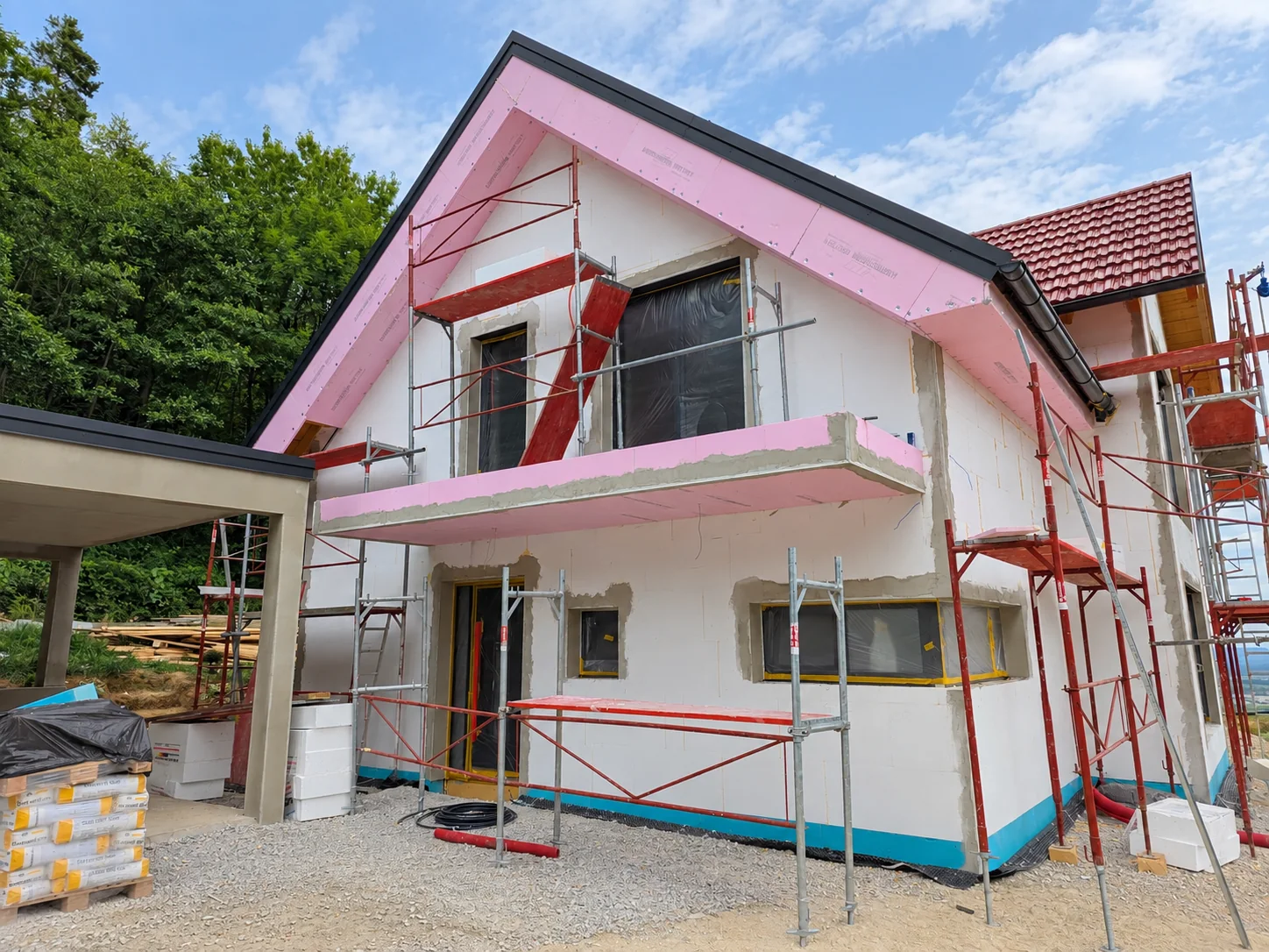 House facade during construction with insulation and scaffolding